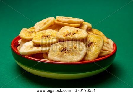 Healthy Snack, Crispy Dehydrated Unsugared Banana Chips In Bowl On Green Background