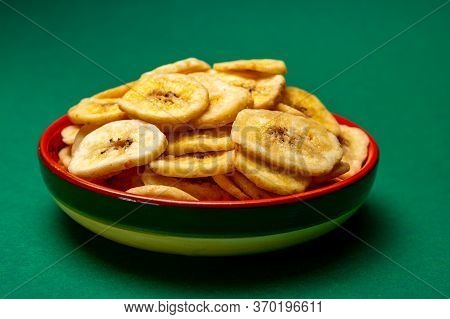 Healthy Snack, Crispy Dehydrated Unsugared Banana Chips In Bowl On Green Background