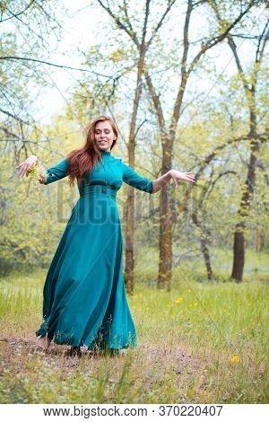 Bootless Woman Dance In Forest. Barefoot Girl In Elegant Dress Posing In Forest On Green Trees Backg
