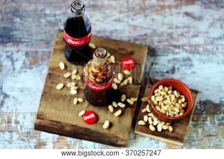 Kharkiv / Ukraine - June 6 2020: Selective Focus. Macro. Coca Cola Bottle With Peanuts. Peanuts With