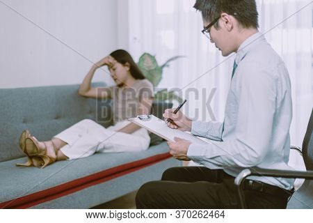 Professional Psychologist Talking With Asian Woman Patient And Writing Notes,therapist Conducting A 