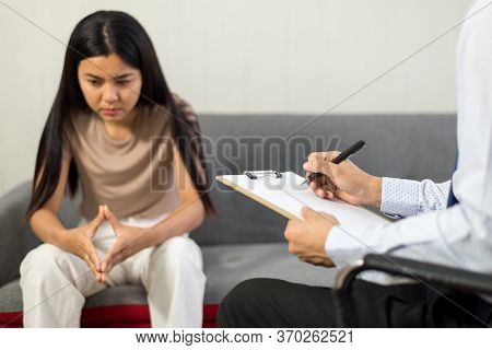 Professional Psychologist Talking With Asian Woman Patient And Writing Notes,therapist Conducting A 