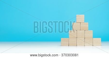 Wooden Blocks As A Pyramid On Blue Background. Success, Growth, Win, Victory, Development Or Top Ran