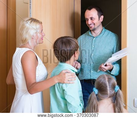 Hospitable Family Greeting Guest At Apartment Entrance.