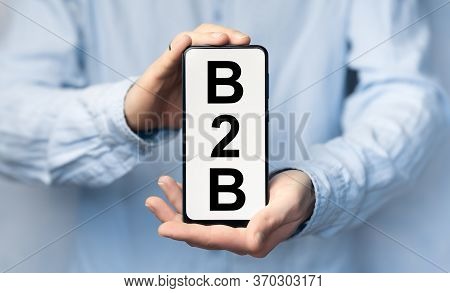 Man's Hand In A Blue Shirt Holding Smartphone With Text B2b