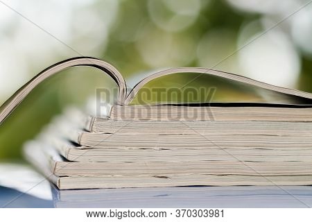 Time To Read Concept. Pile Of Stacked Magazines On The Blur Background. One Top Magazine Is Open. Cl