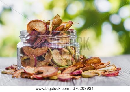Homemade Apple Chips. Dried Fruit. Healthy Snack In A Glass Jar And On A Wooden Surface With Green B