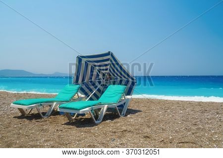 Two Sunbeds On The Sandy Beatch Against Sea. Sea Resort.