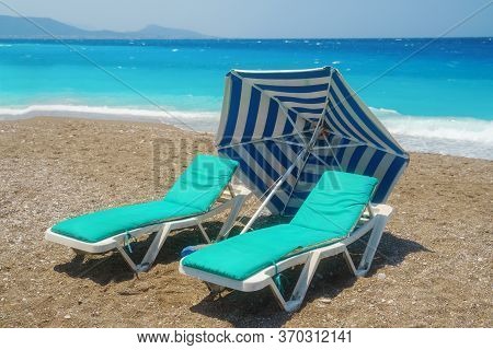 Two Sunbeds On The Sandy Beatch Against Sea. Sea Resort.
