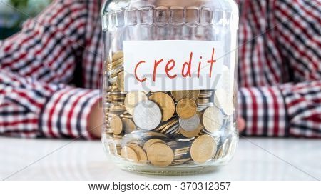 Glass Jar Fulll Of Coins Labeled Credit. Concept Of Finance, Economy Growth And Bank Savings