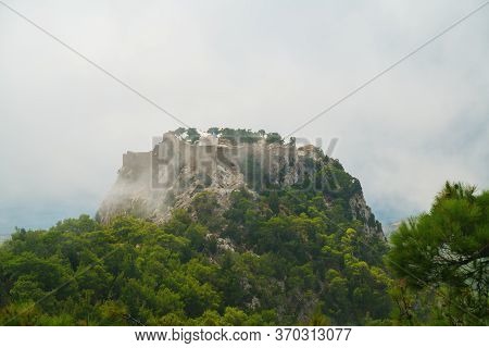 Picturesqueview On Monolithos Castle Perched Atop A 100-meter Tall Sheer Rock Face Overlooking The M