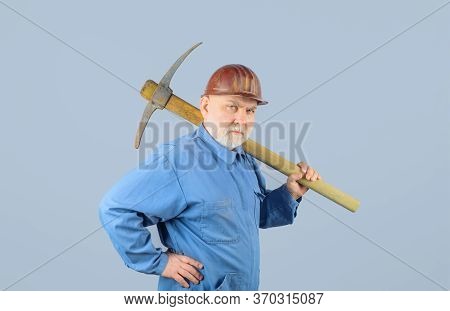 Male Miner Worker In Coveralls With Pickaxe. Construction And Building Works. Bearded Man In Uniform