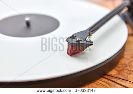Vintage old-fashioned turnable record player with retro vinil disc on a wooden table, copy space. Close up view. Popular disco trends 60s, 70s, 80s, 90s.