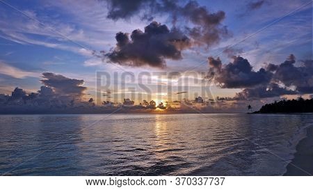 Beautiful Sunset In The Maldives. Smooth, Calm Ocean Surface, Picturesque Clouds. The Sun Is Low Ove