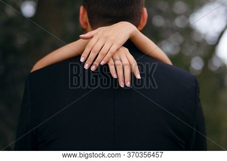 The Girl Embraces The Neck Of The Groom, The Beautiful Bride Walks In The Park With The Groom, On He