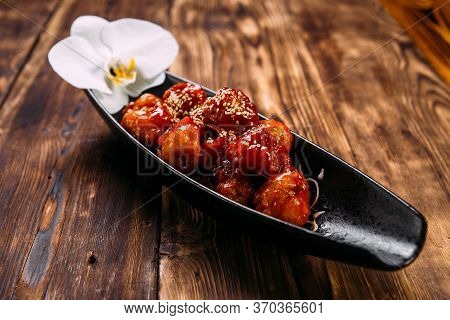 Asian Batter Chicken With Spicy Sweet Sauce On The Black Plate On The Wooden Table, Horizontal