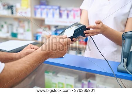 Pharmacist Holding Terminal, Man Paying With Credit Card. Crop Of Unrecognizable Customer Making Pay