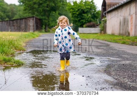 Little Toddler Girl Wearing Yellow Rain Boots, Running And Walking During Sleet On Rainy Cloudy Day.