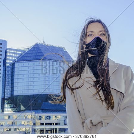 Portrait Of Brunette Woman In A Protective Medical Mask On A Cityscape Background. Virus Protection.