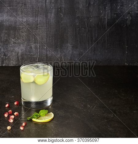 Ginger lemonade drink side view. Glassful of seasonal non-alcoholic concoction. Glass of refreshing summer temperance beverage. Sweetened lemon juice and water mix. Lemon-flavored refreshment with ice