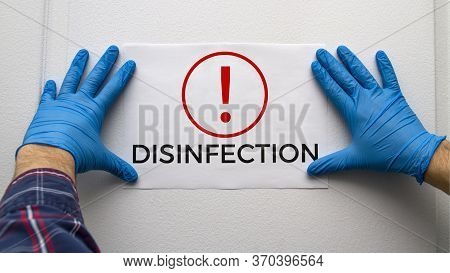 A Man In Blue Protective Gloves Attaches A Disinfection Announcement On The Door