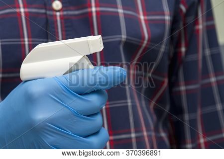 A Man In Blue Protective Glove Holds A Bottle With A Disinfectant. Protection From Bacteria And Viru
