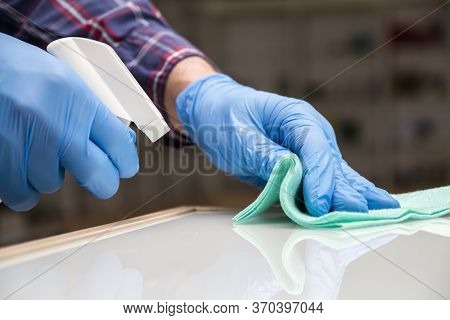 A Man In Blue Protective Gloves Disinfects The Surfaces Of An Audio And Video Equipment Store Using 