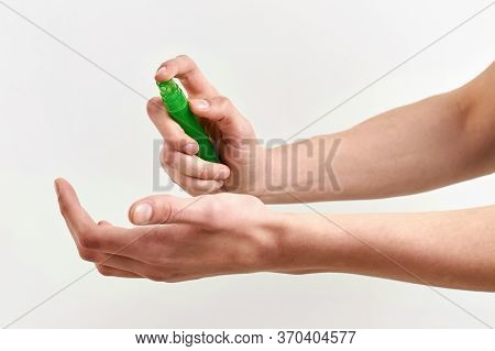 Male Hand Is Spraying Hand Sanitizer. Virus Prevention. Light Background, Closeup.