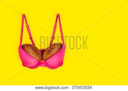 Two Coconuts In Bright Pink Bra On Yellow Background. Woman Breast Metaphor. Plastic Surgery, Implan
