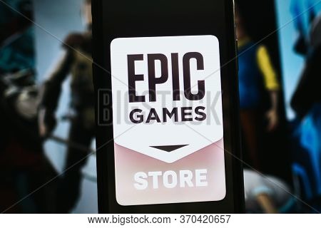 Hand Holding Smartphone With Epic Games Store Logo On The Screen. High Quality Photo