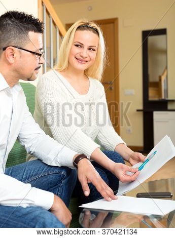 Woman And A Social Worker Sitting On A Sofa At Home. Woman Asks Caseworker How To Properly Fill In D