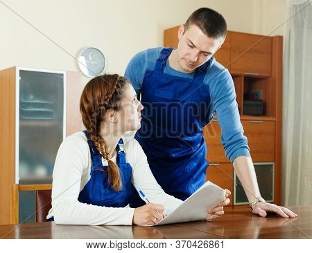 Serious Workers In Uniform Filling In Questionnaire At Table