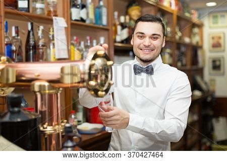 Modern Bar With Bottles At Background And Happy Smiling Male Bartender.