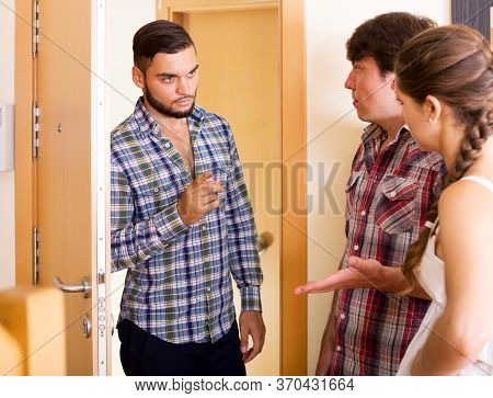 Unhappy Neighbor Standing At Entrance And Complaining About Noise. Focus On The Man
