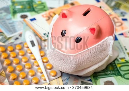 Piggy Bank In A Mask On A Background Of European Currency.the Concept Of Coronavrius Epidemic