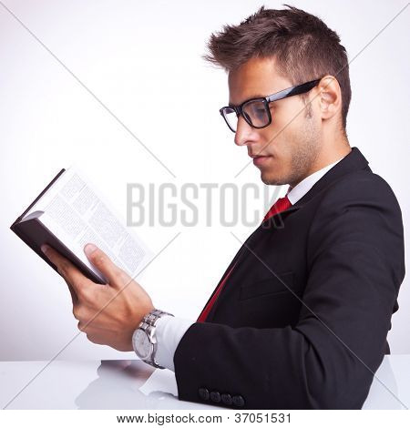 side view of a business man reading an interesting book at his desk