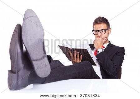 ธุรกิจคนที่โต๊ะของเขานั่งมากผ่อน อ่านหนังสือทริลเลอร์