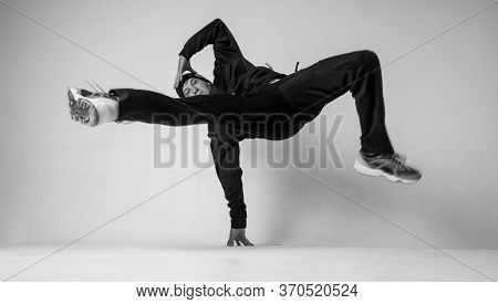 A Man Hip Hop Dancer Or Bboy Freezes In One Pose On A White Background. Bboy Doing Stylish Stunts.