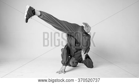 A Man Hip Hop Dancer Or Bboy Freezes In One Pose On A White Background. Bboy Doing Stylish Stunts.