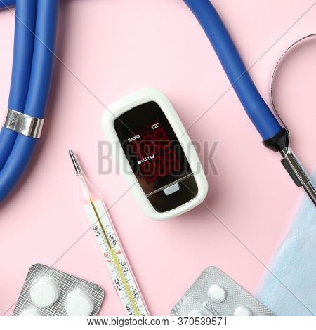 Flat Lay Composition With Fingertip Pulse Oximeter And Medical Items On Pink Background