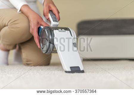 A Woman Vacuuming Furniture In A House With A Hand-held Portable Vacuum Cleaner.