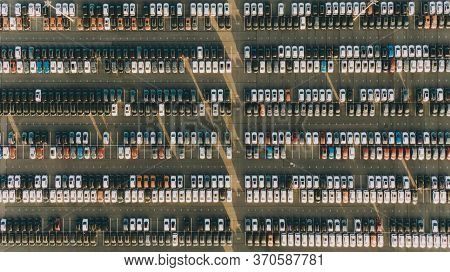 New Cars Stand In Even Rows In The Territory Of An Automobile Plant, Aerial View. The Economic Crisi