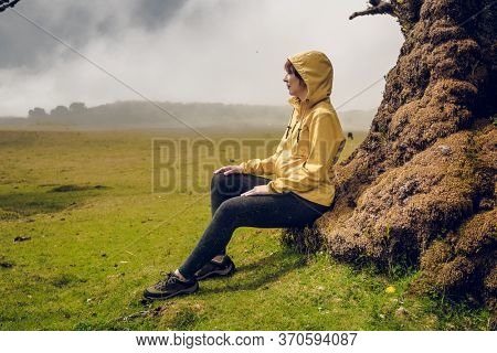 Woman resting near an Ancient tree and enjoying the view