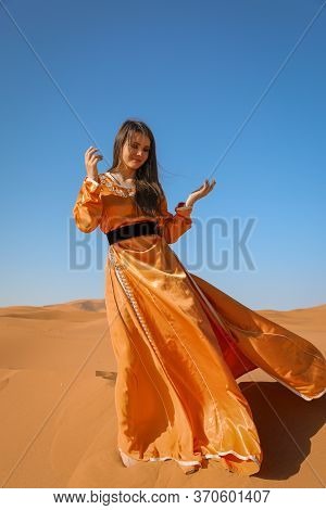 Beautiful Young Girl In Moroccan Dress In Sahara Desert.