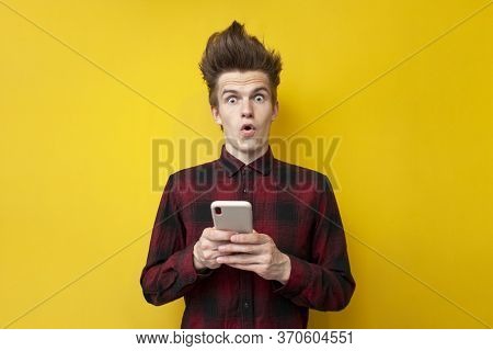 Shocked Guy With Funny Hairstyle Use Smartphone On Yellow Isolated Background, Hipster Holds Phone A