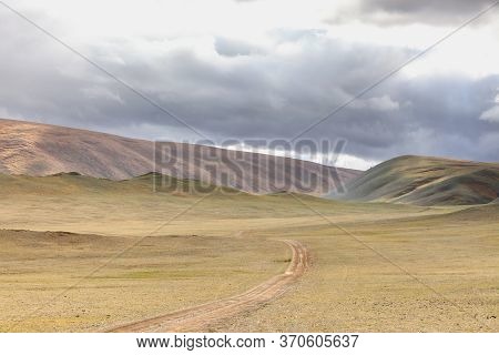 Winding Dirt Road Through Lush Rolling Hills Of Central Mongolian Steppe. Mongolian Altai. Typical V