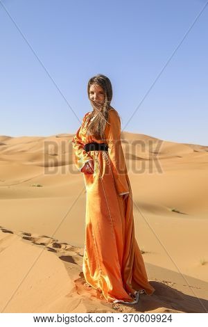 Beautiful Young Girl In Moroccan Dress In Sahara Desert.