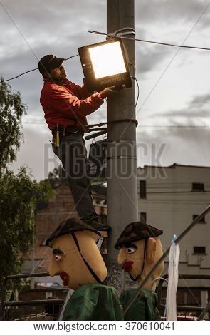 Workman Attaches Led Lgiht To Pole For Festival