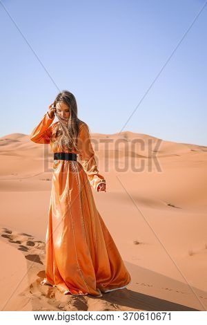 Beautiful Young Girl In Moroccan Dress In Sahara Desert.