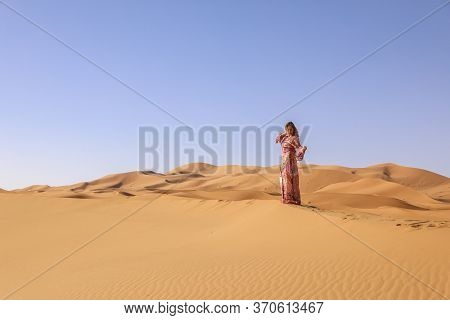 Girl In Moroccan Dress In Sahara Desert.